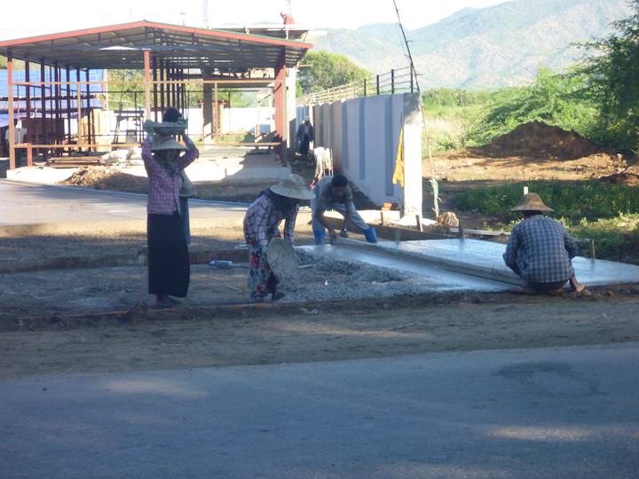 The women carry the concrete from the mixer to the pour on their heads, while the men carry in front of themselves.