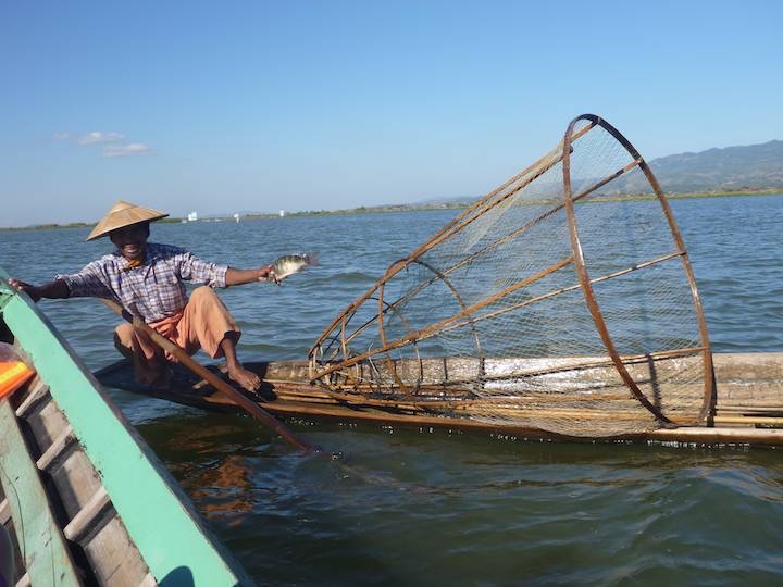 A fisherman shows off his catch and gets some cash for a photo